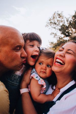 Close-up candid family photo showing joyful expressions and laughter outdoors.