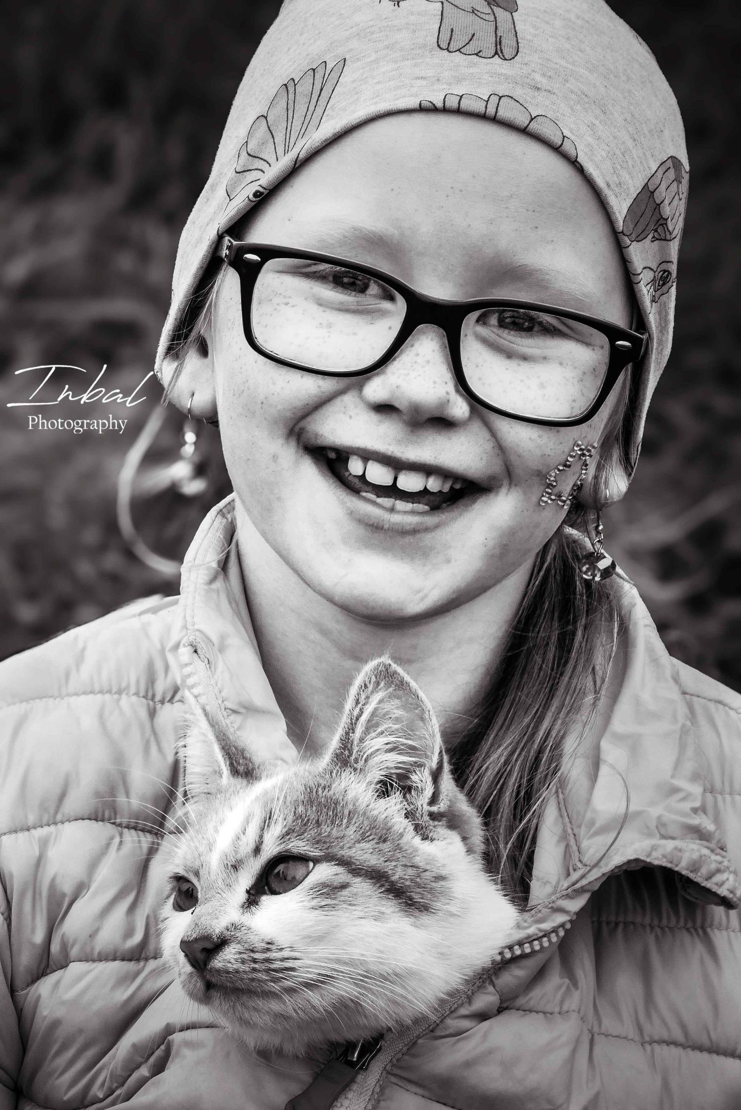 A little girl from Iceland, smiles while holding her cat inside her jacket.