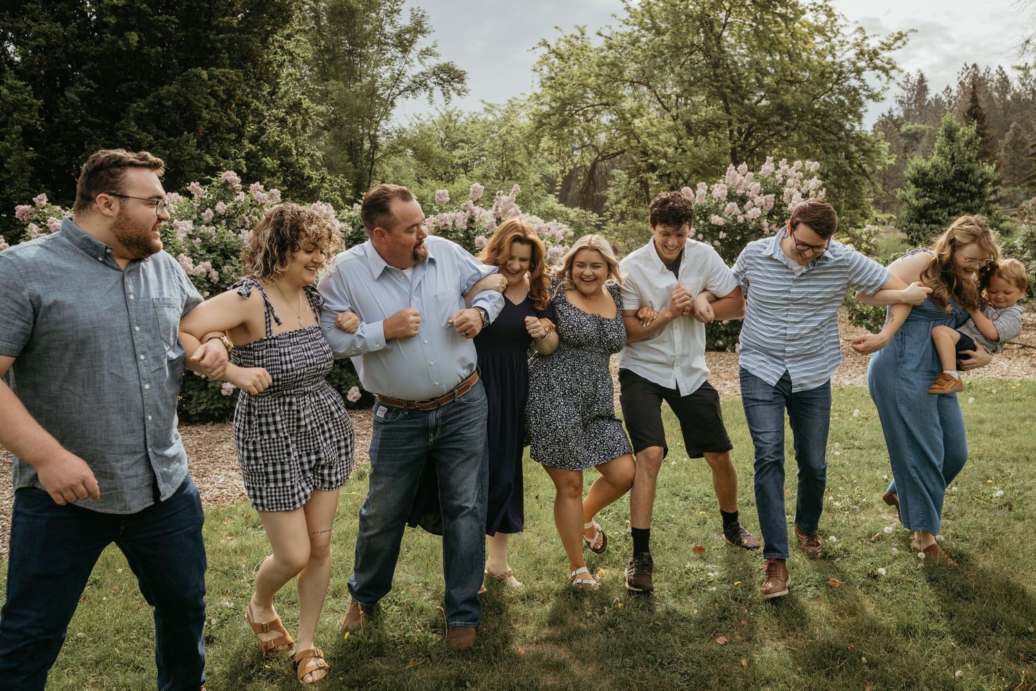 Joyful group of friends dancing and celebrating outdoors in a sunny garden setting.
