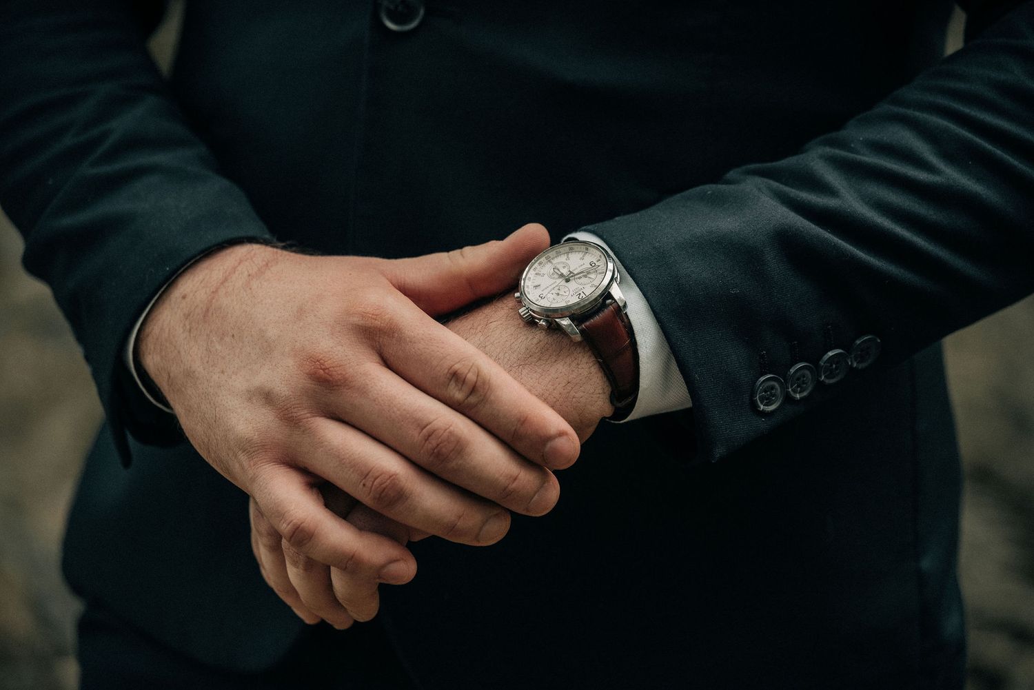 Elegant wristwatch on formal suit sleeve with detailed focus on timepiece.