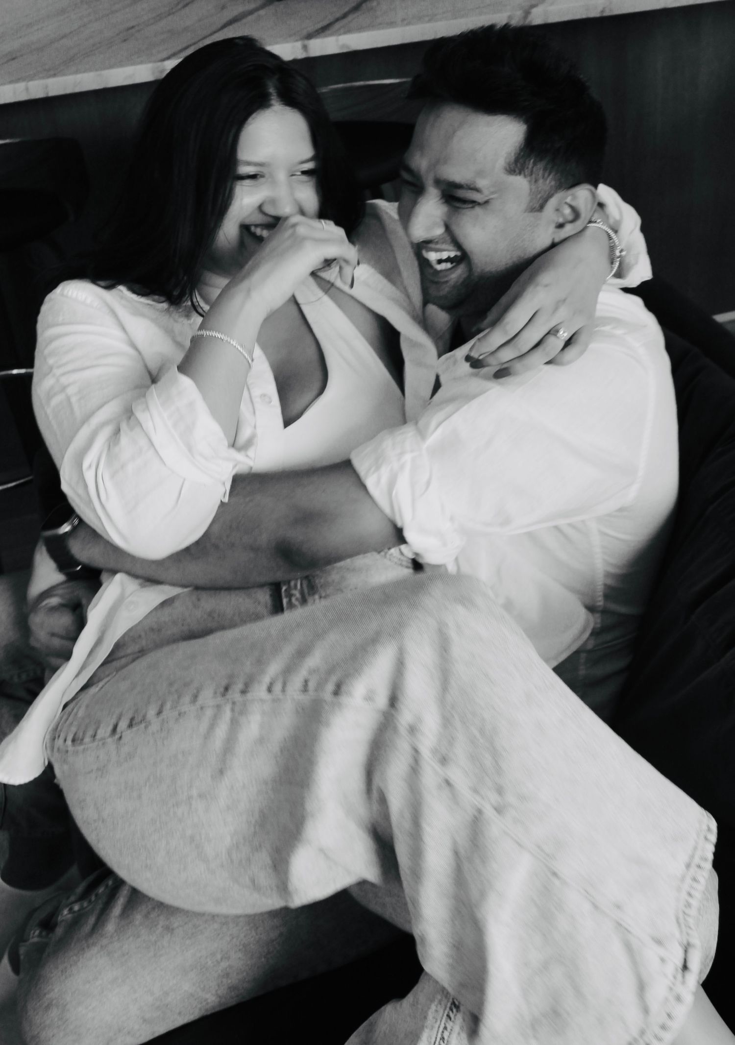 A black and white photo showing laughter and joy between two people in casual outfits.