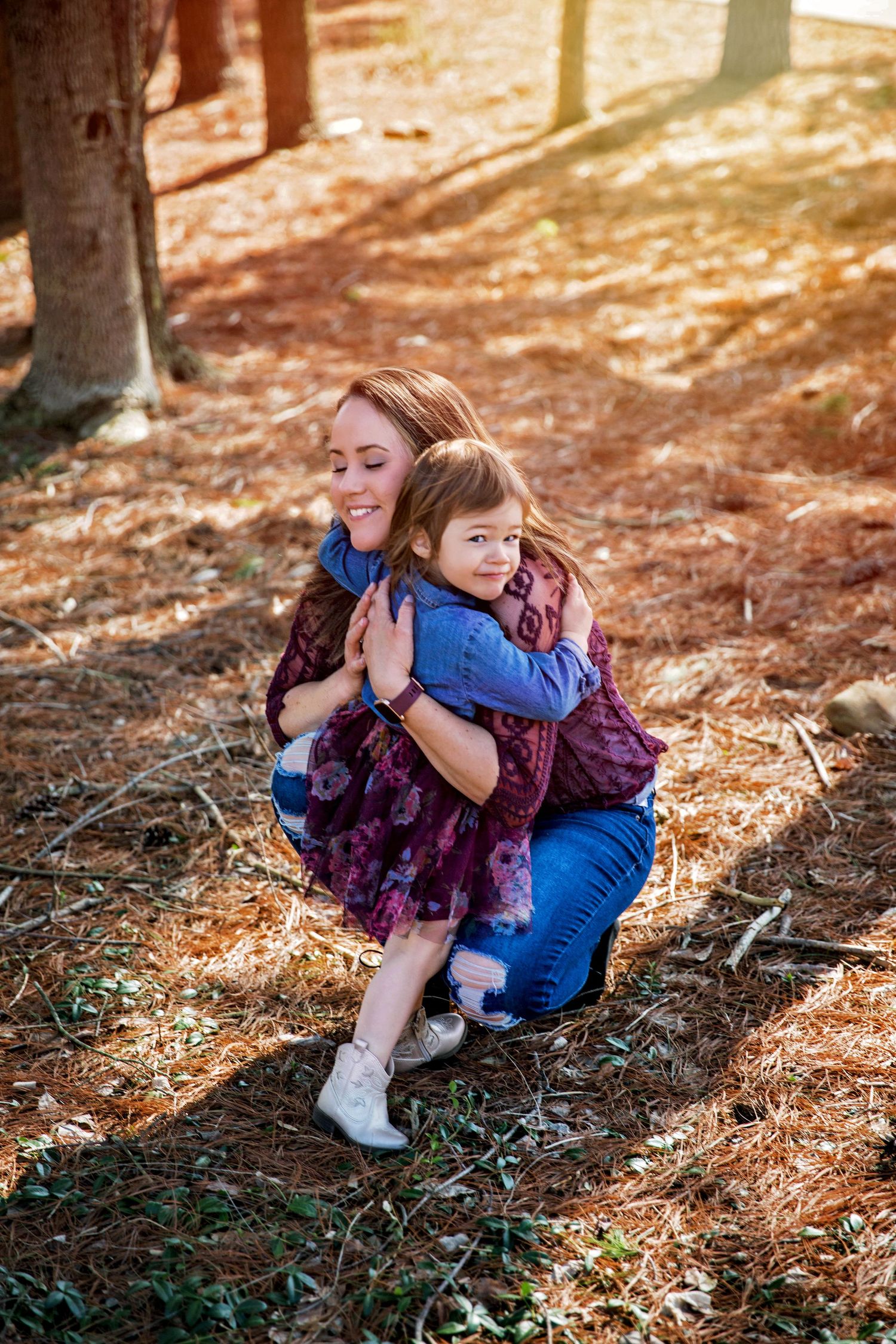 A joyful embrace shared in autumn sunlight among fallen pine needles.