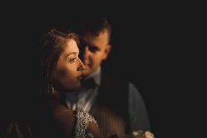 An intimate low-light portrait capturing a tender moment during a wedding reception.
