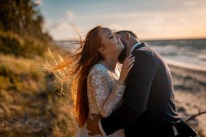 Sunset beach wedding portrait with bride's hair flowing in coastal breeze.
