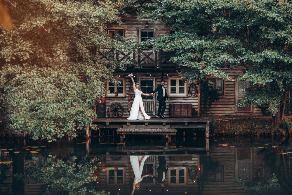 A rustic wooden lodge with a balcony reflected perfectly in a calm lake.