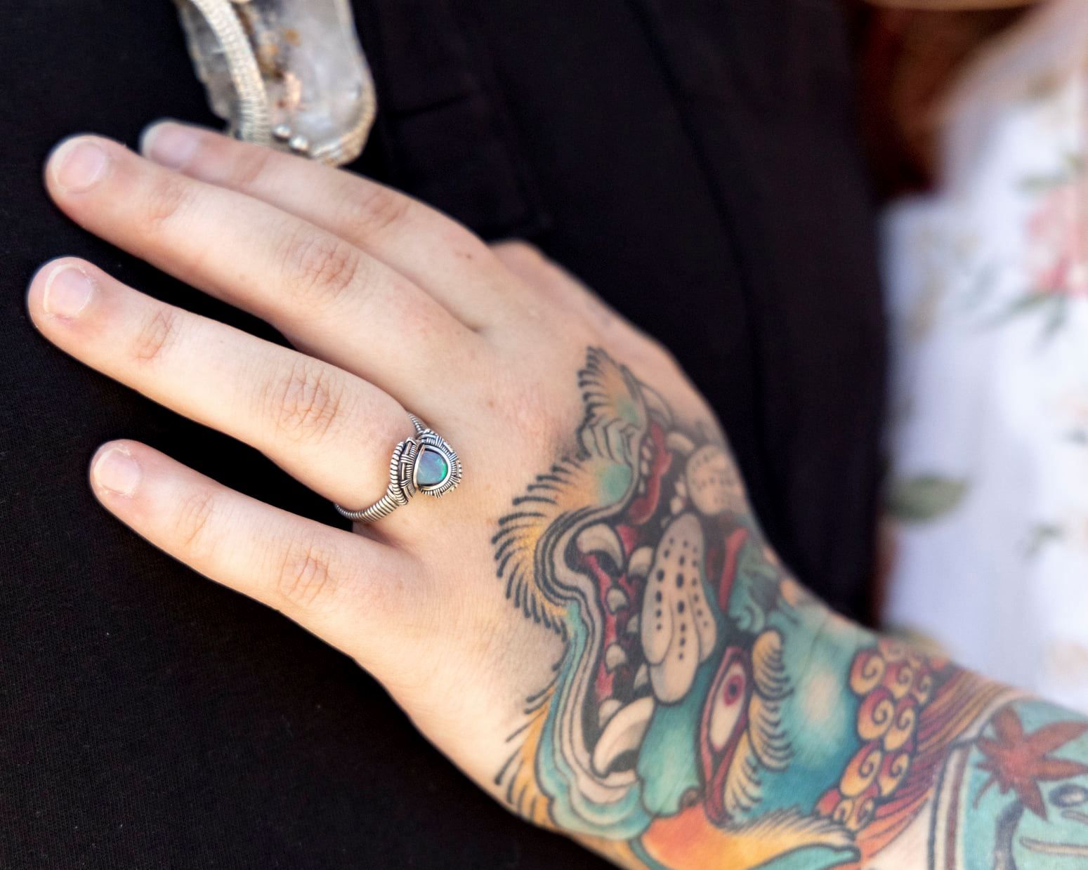 Detailed shots of colorful tattoo artwork on hands and fingers against a dark background.