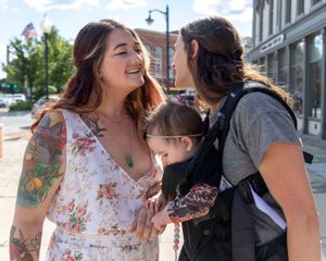 A couple shares joyful moments outdoors on a sunny day in an urban setting.