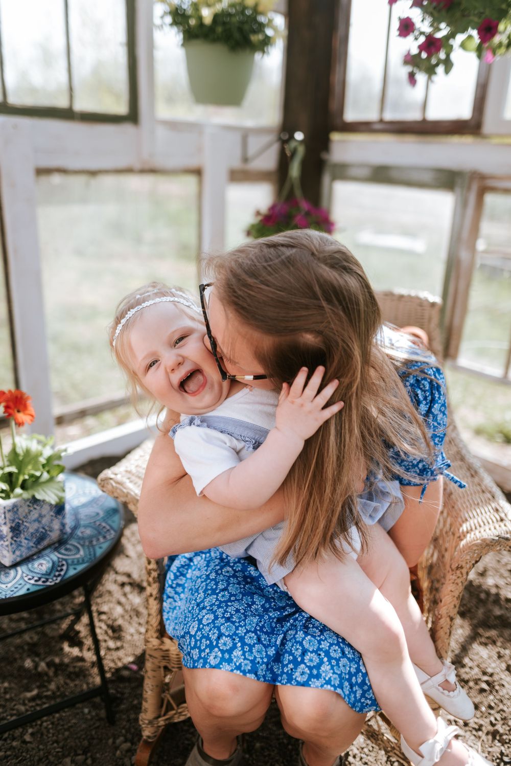 Pure joy and laughter captured in an intimate moment inside a sunlit greenhouse with flowers.