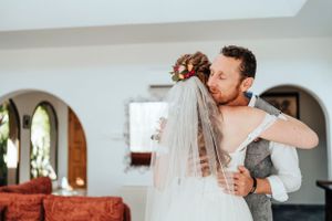 A tender embrace between newlyweds in a room with arched doorways on their wedding day.