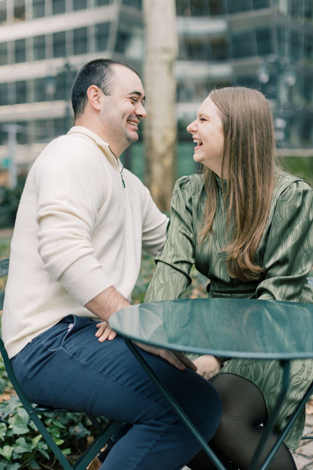 Happy couple sharing a laugh while sitting in urban park setting.