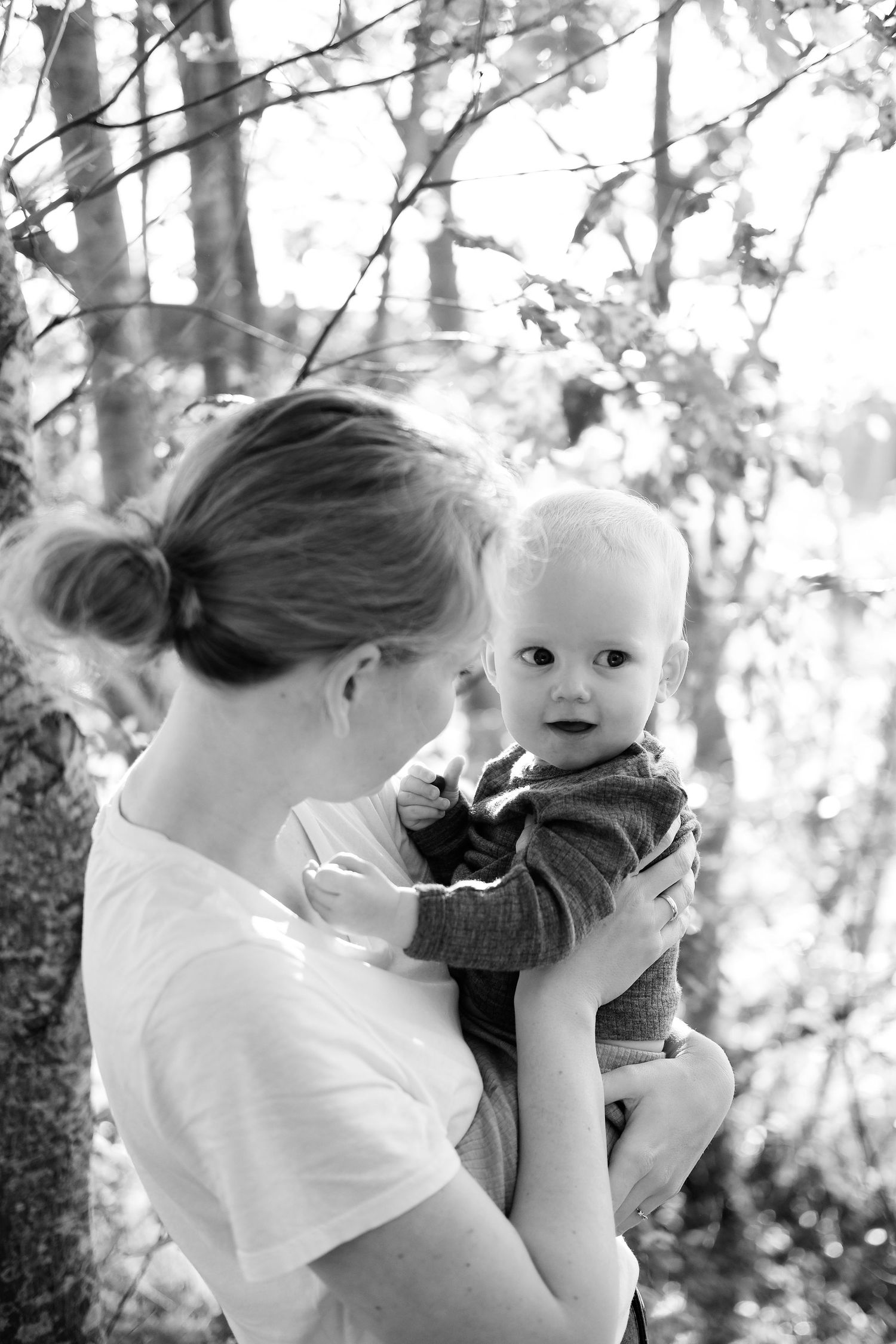 A black and white portrait of parent and baby surrounded by forest trees.