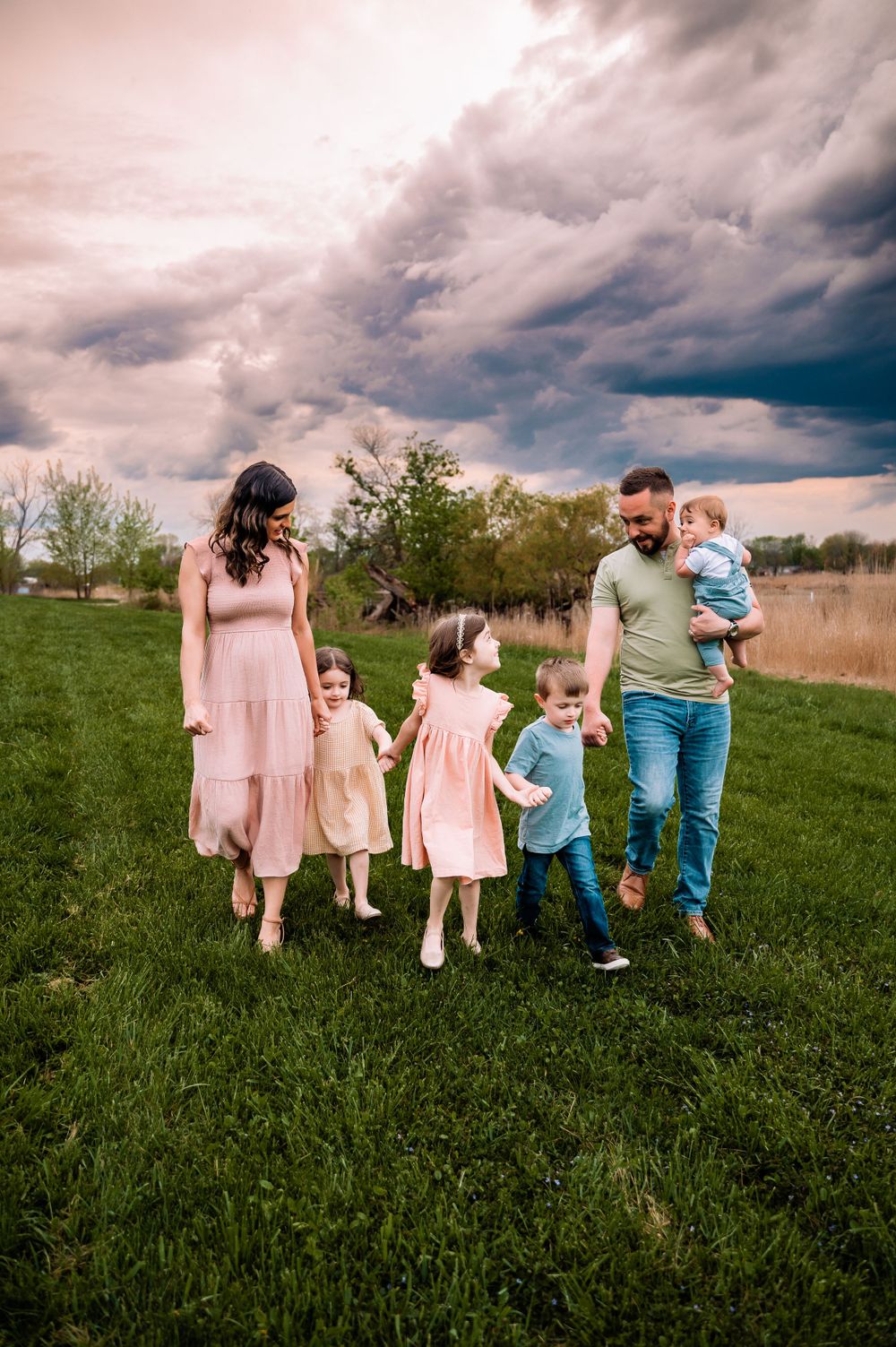 Family with four young children walking holding hands in field