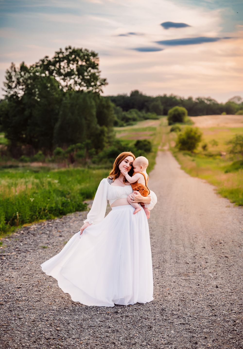 mother holding baby in one hand and skirt in the other
