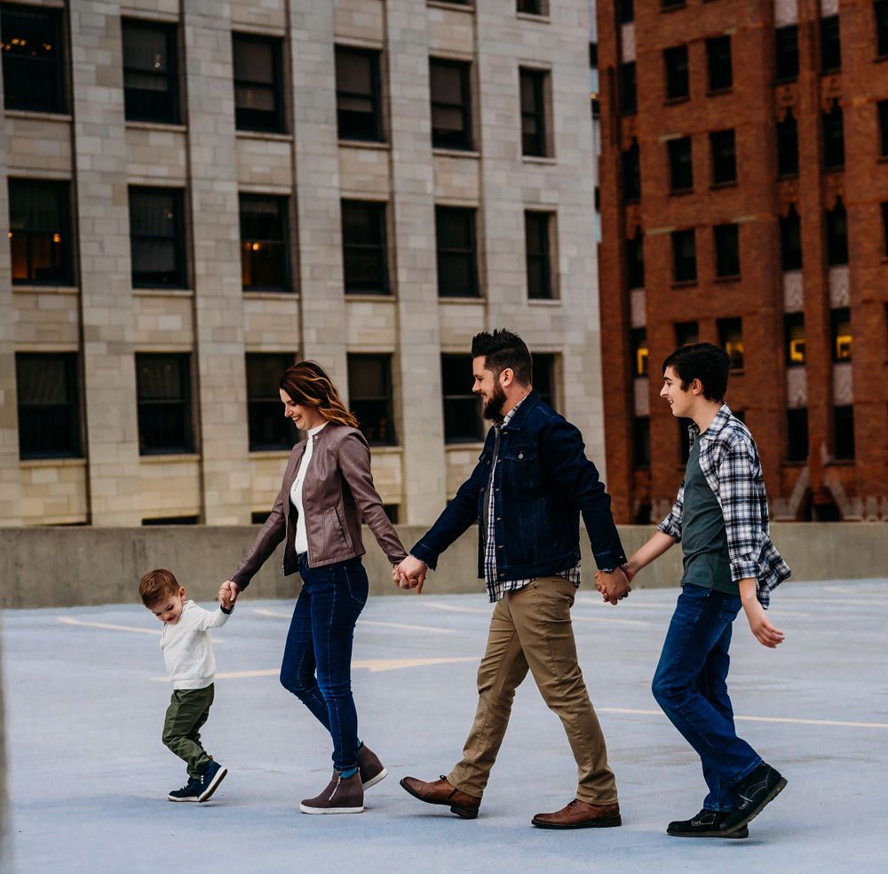 family walking holding hands against buildings on Detroit roof top