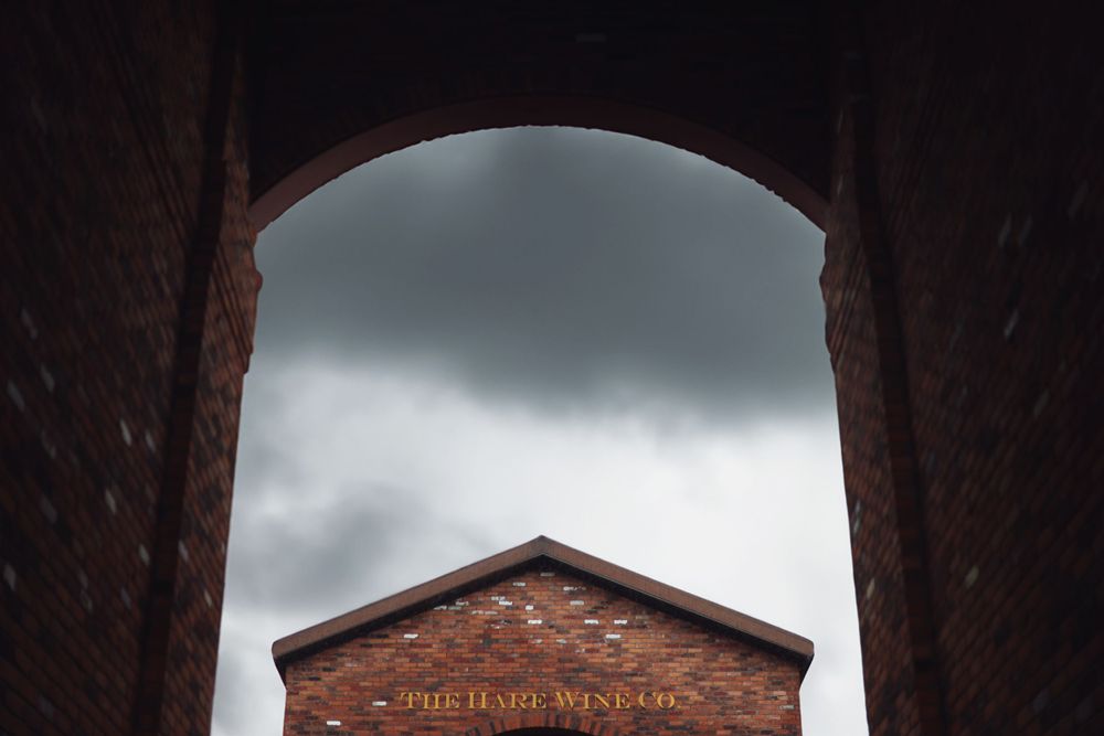 Dramatic view of brick building through archway with stormy sky overhead.