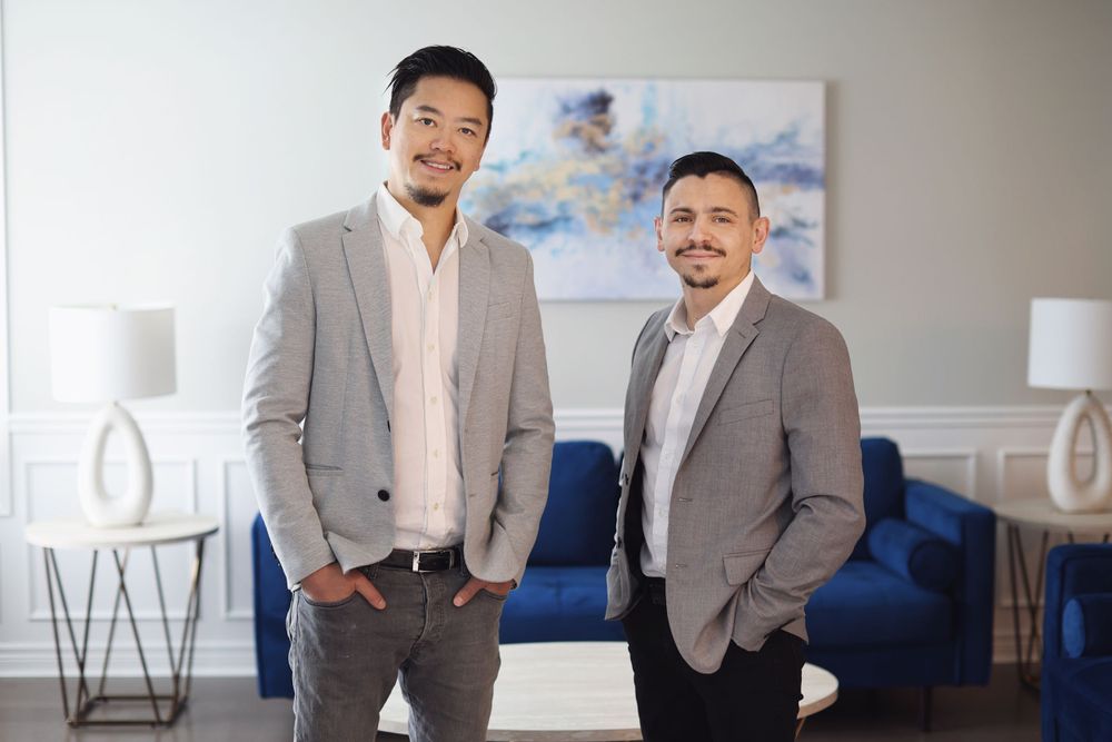 Two professionals in business attire standing in modern office with blue furniture and abstract art.