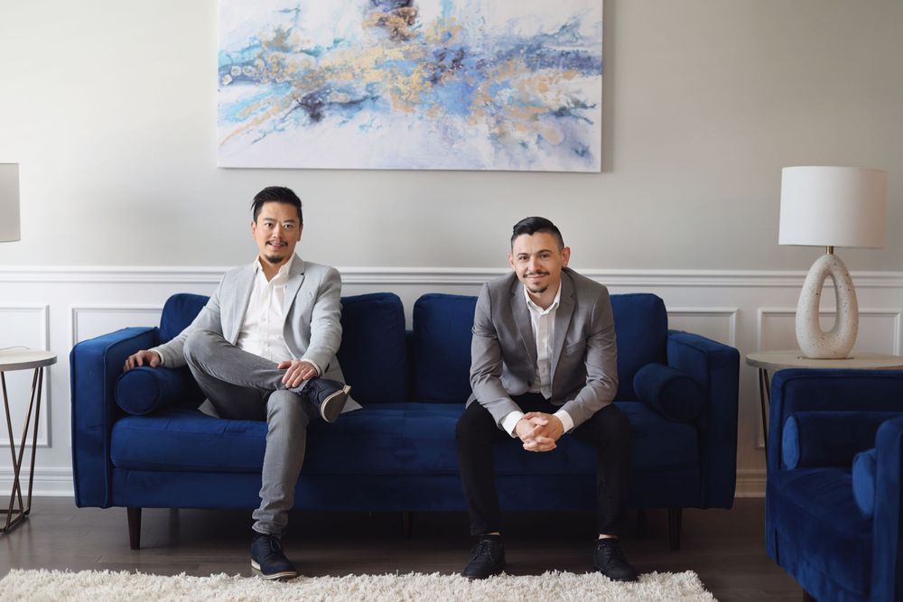 Two colleagues relaxing on blue couch in modern office with abstract wall art.