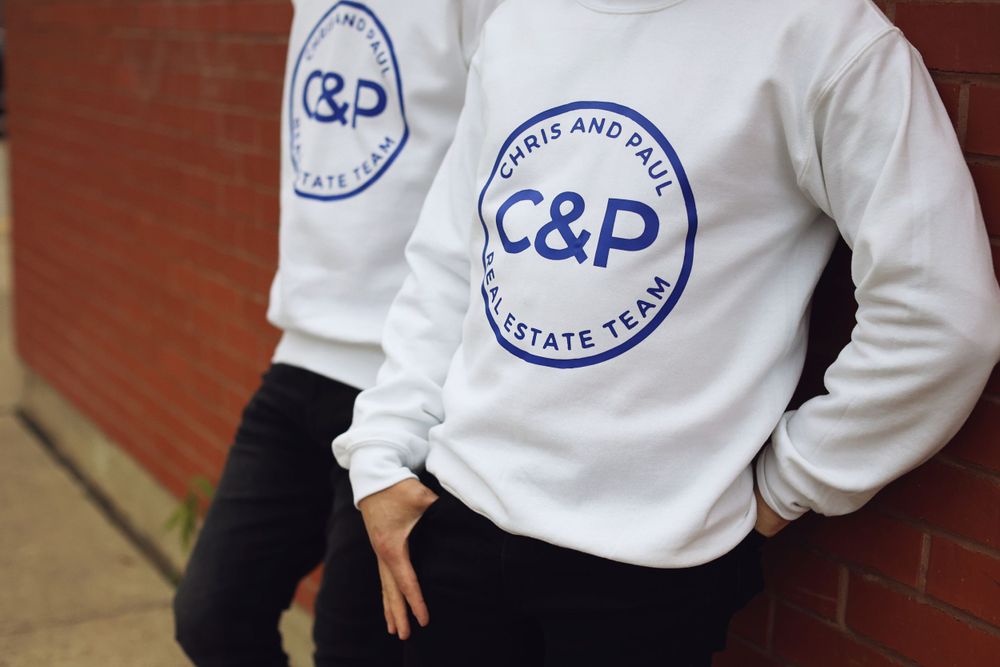 Close-up of white sweatshirt with blue C&P Estate Team logo design.