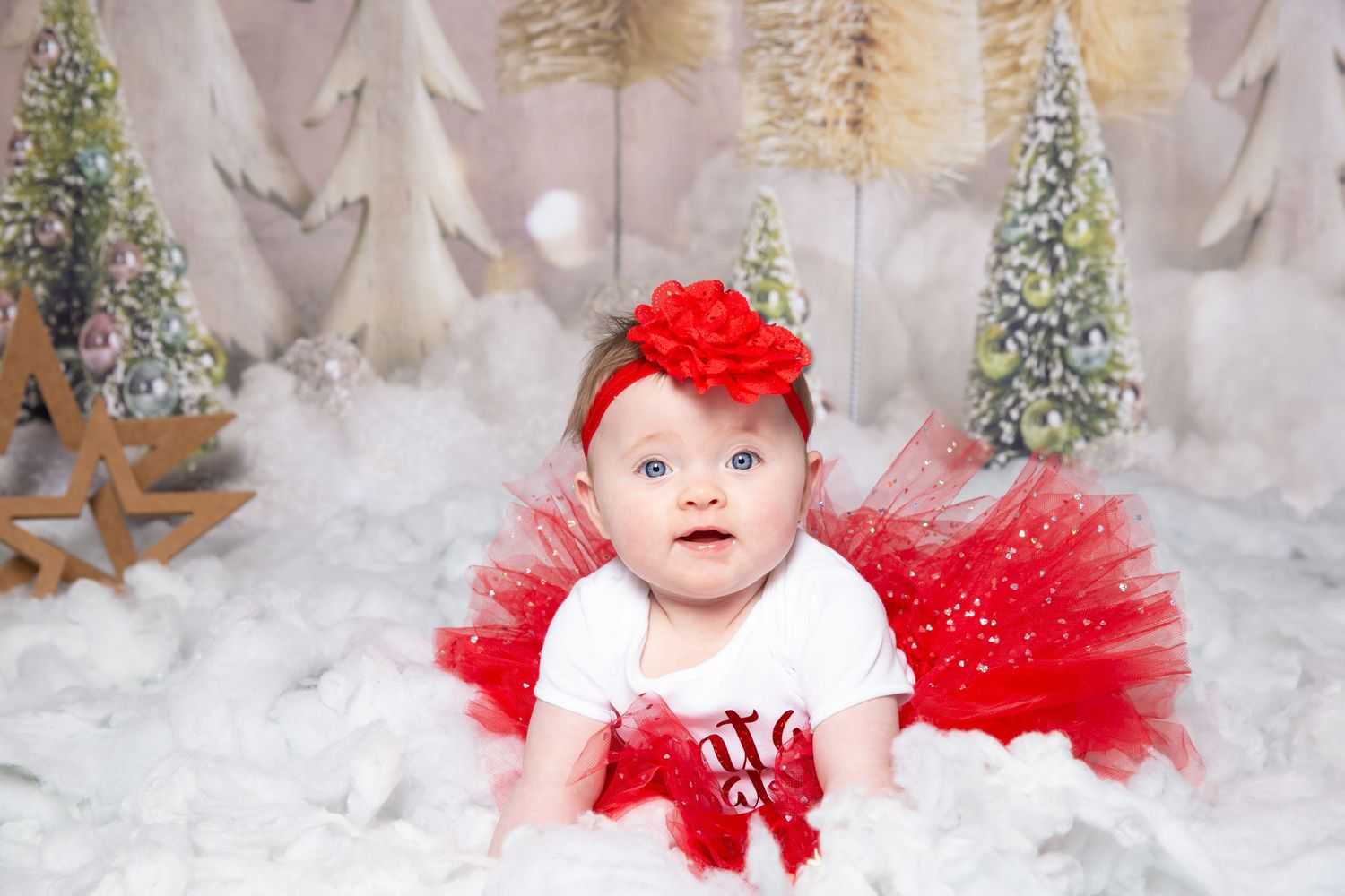 baby in snow with red tut and headband