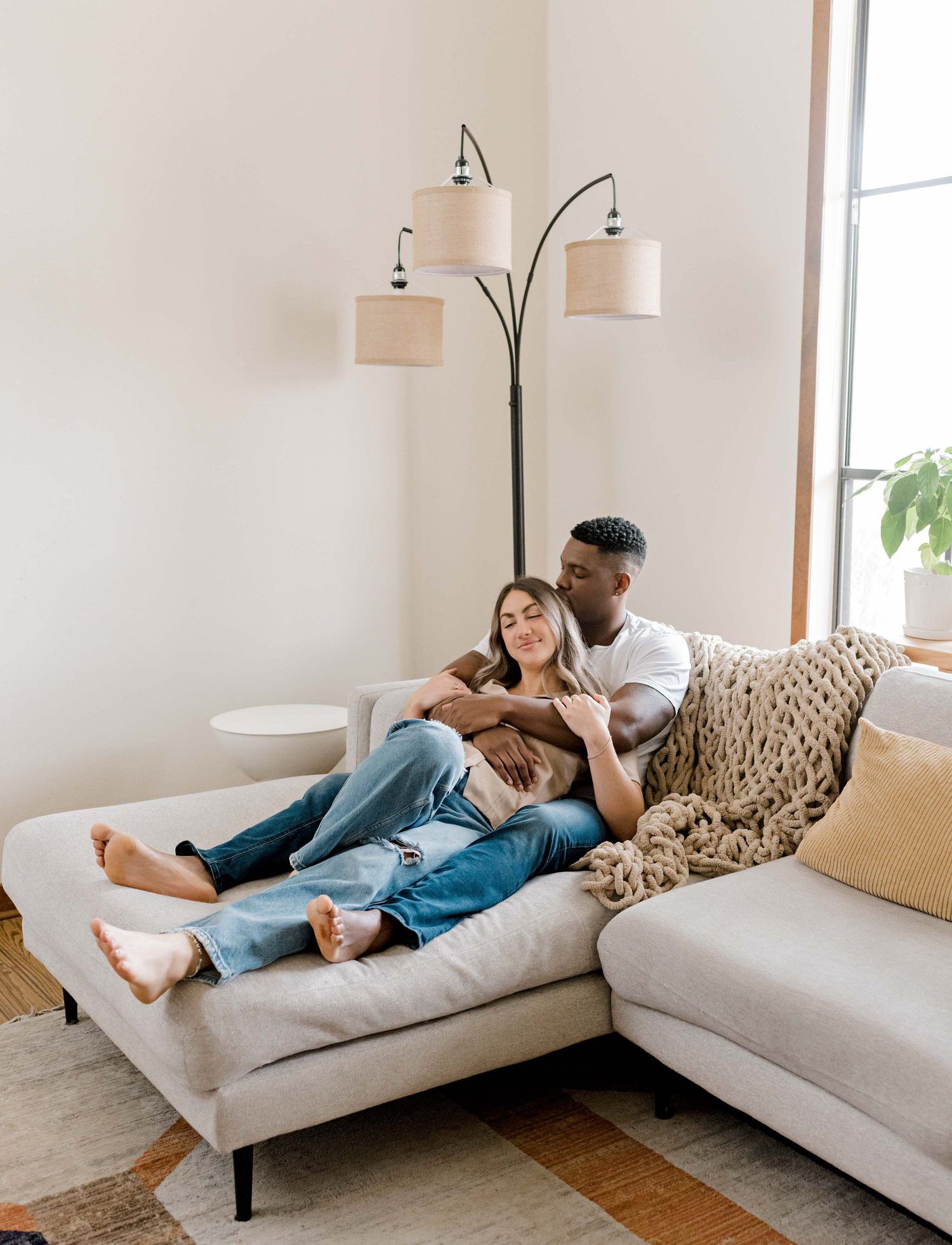 A cozy scene of a couple relaxing together on a sectional sofa beneath a modern floor lamp.