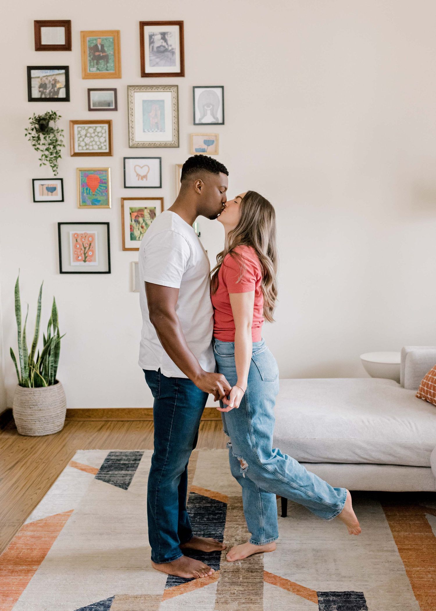 Romantic moment shared between a couple against a wall decorated with framed artwork.