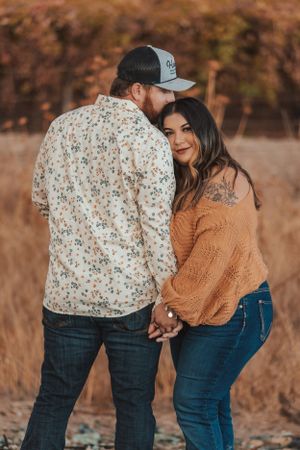 Couple in casual attire sharing intimate moment against autumn backdrop.