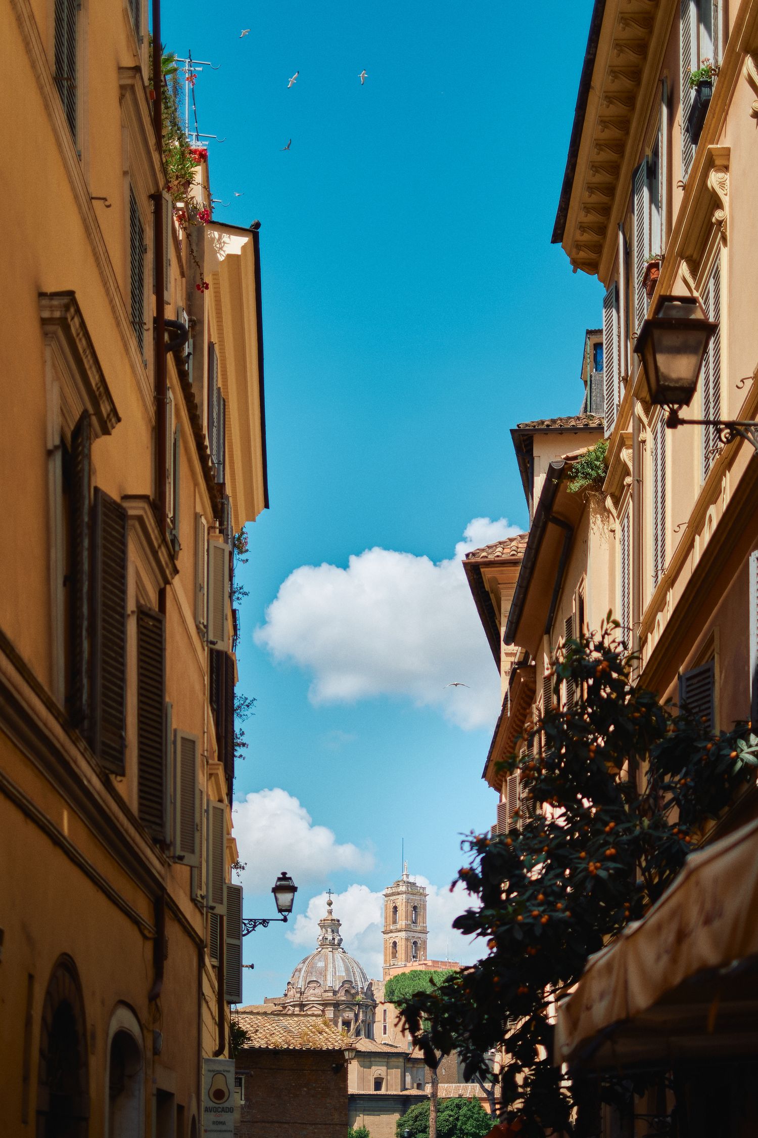 Picturesque Italian street view with ochre buildings and church tower visible between buildings.
