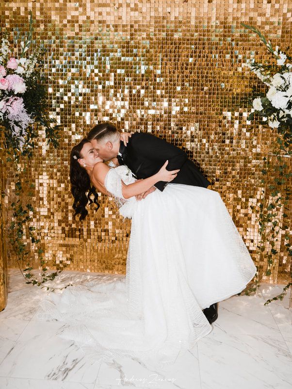Wedding couple poses against shimmering gold sequin backdrop in romantic photo series.