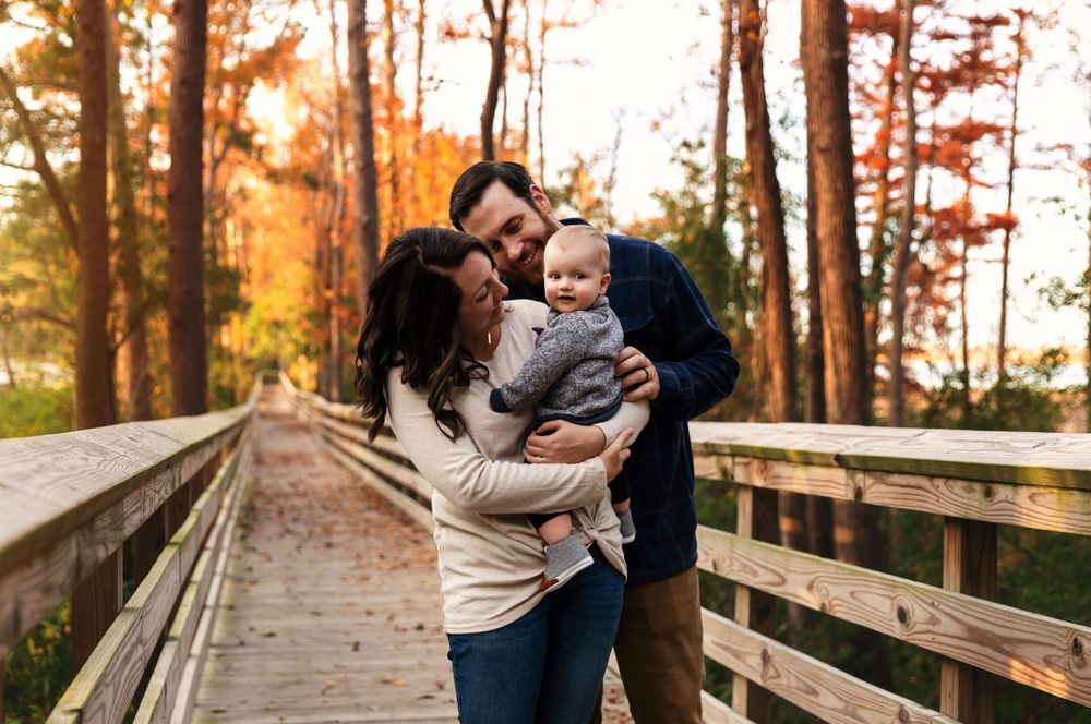 Natural lifestyle family photography on a wooden pathway surrounded by fall colors.