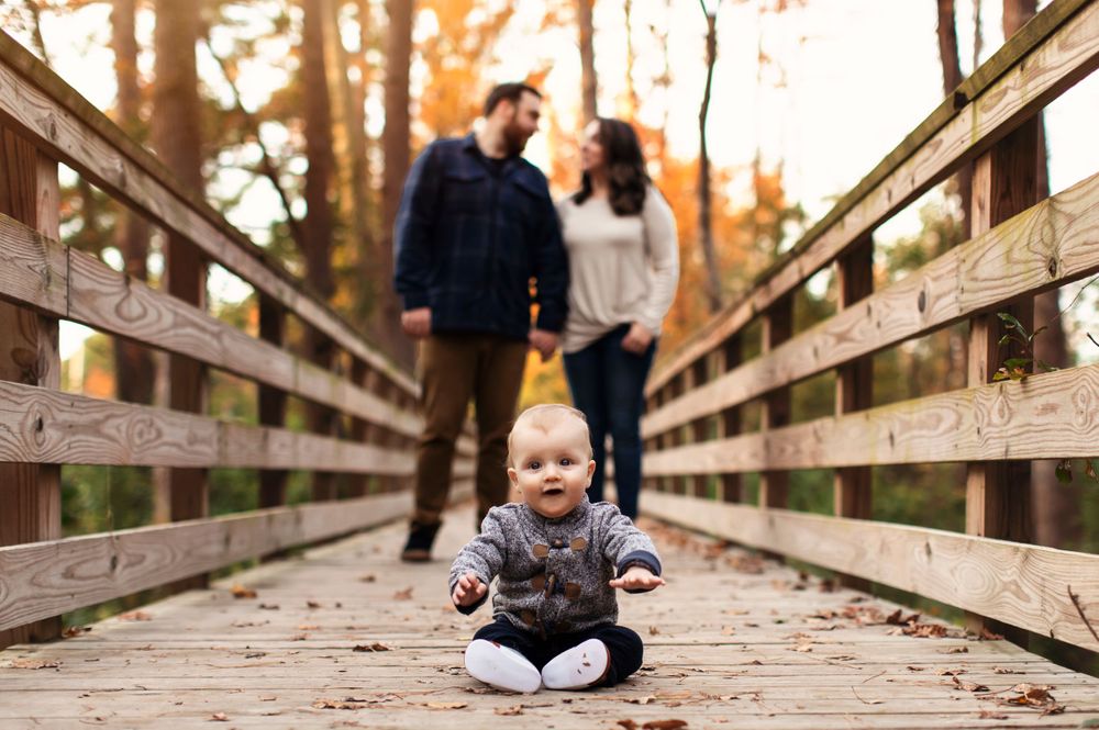 Casual family photos taken on a wooden boardwalk with natural autumn scenery.
