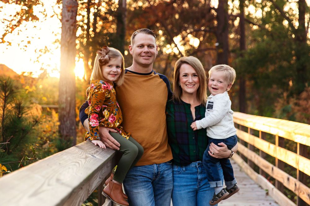 Candid family moments captured on a wooden walkway during sunset with fall foliage.