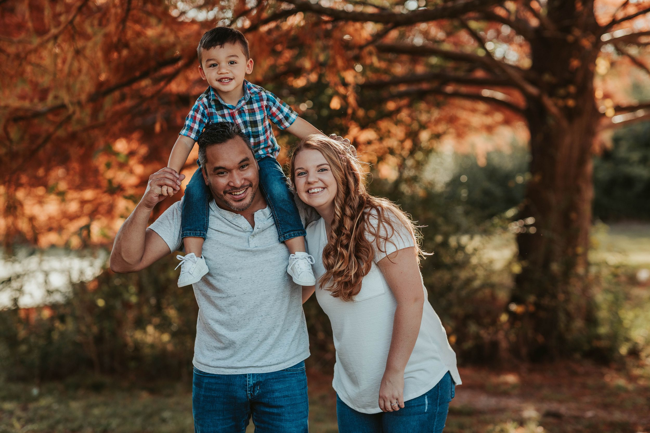 Family enjoying a sunset photo session surrounded by warm autumn colors and falling leaves.