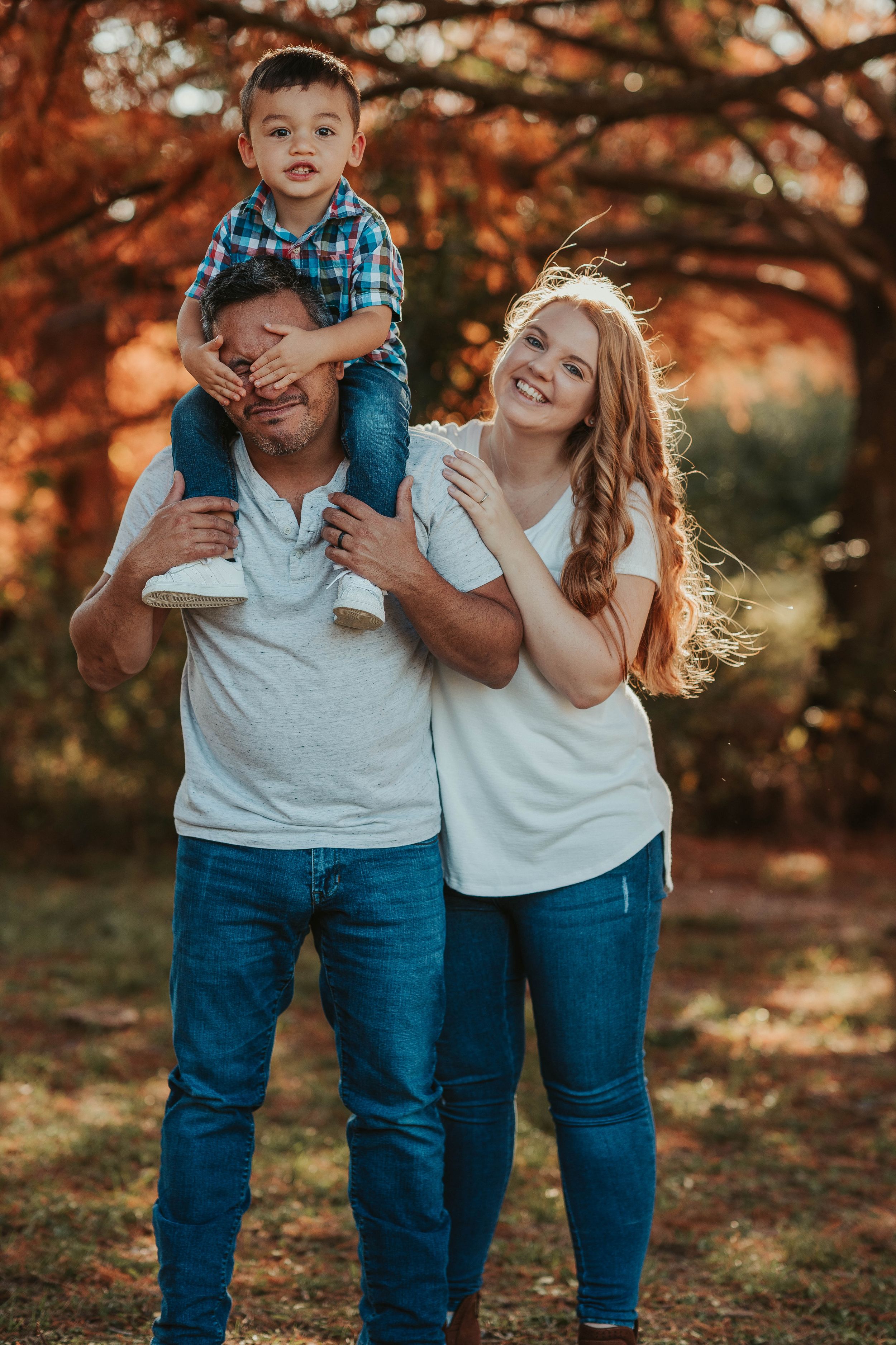 Candid family lifestyle portrait with coordinating denim and white outfits in a fall setting.
