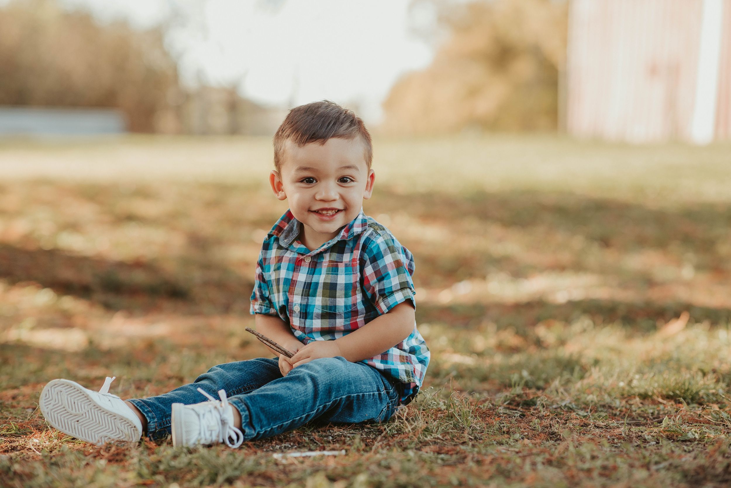 Child playing and posing on autumn grass during an outdoor photo session.