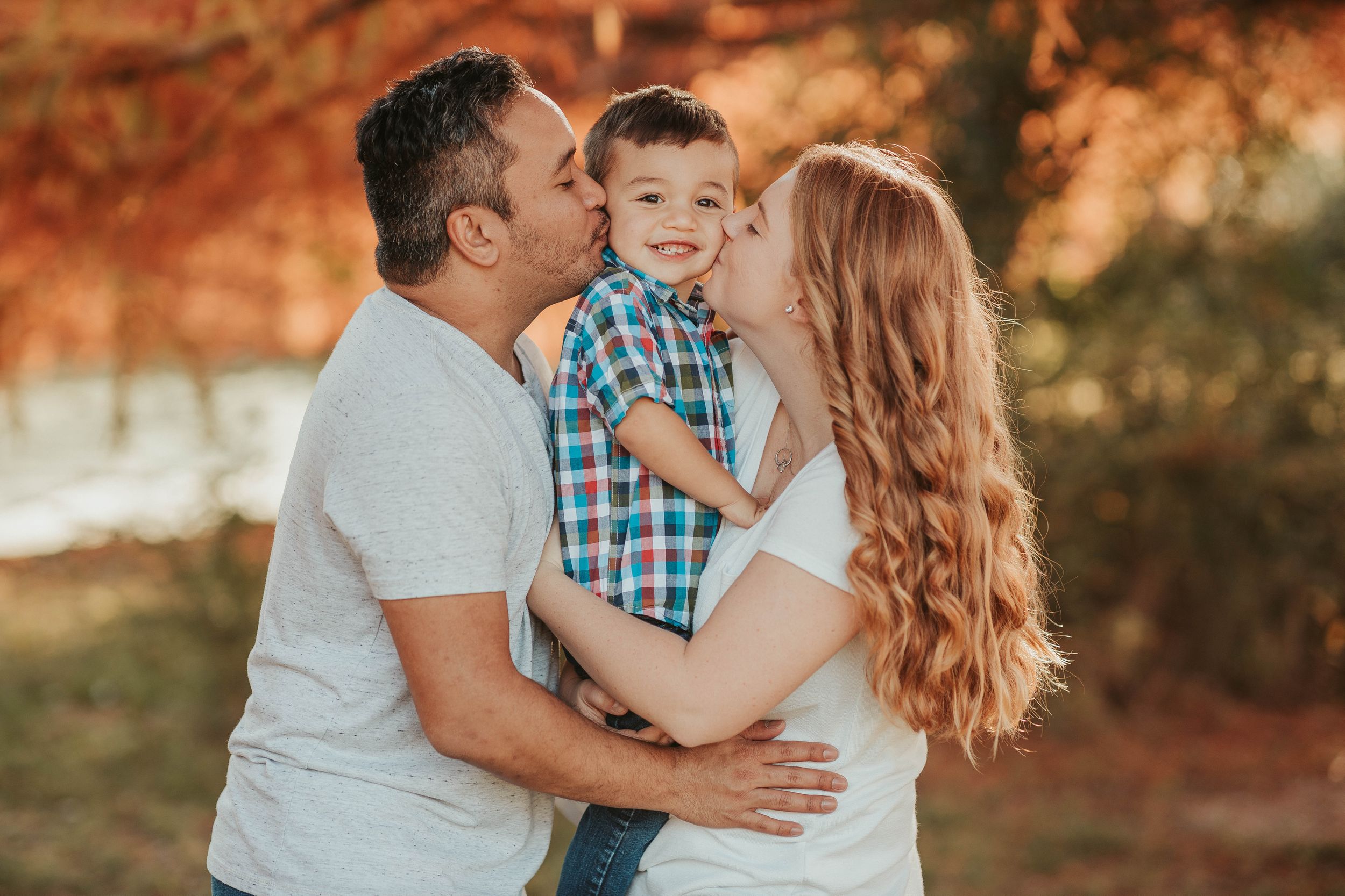 Intimate family moment captured during golden hour with fall colors in background.