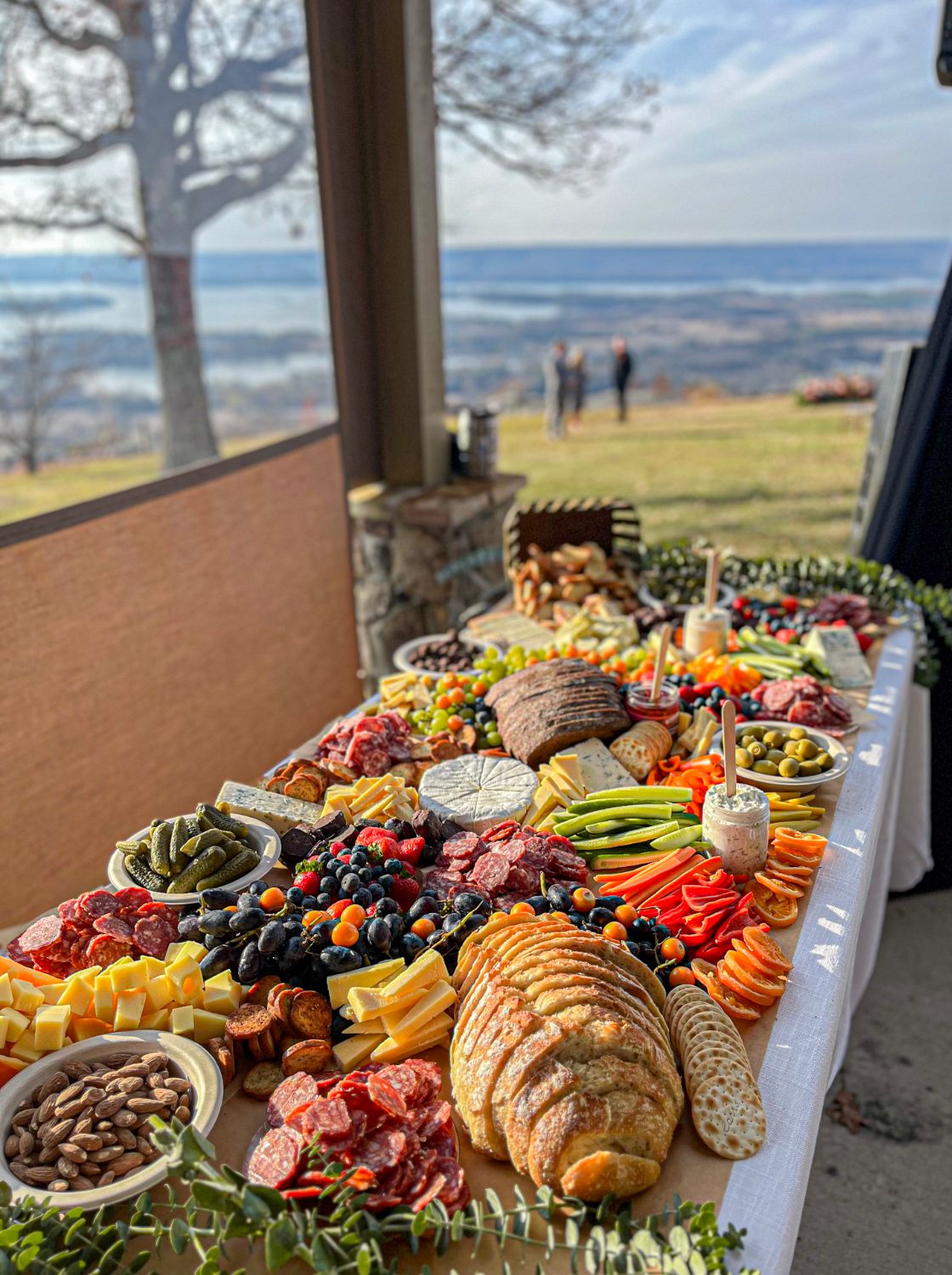 Expansive charcuterie display overlooking mountain vista with meats, cheeses and fresh vegetables.