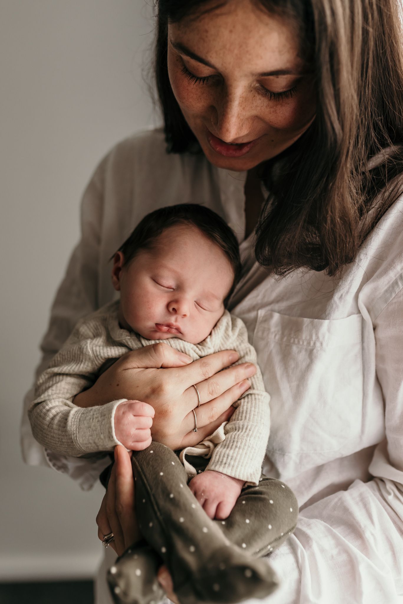 Peaceful newborn baby sleeping soundly in cream colored outfit.