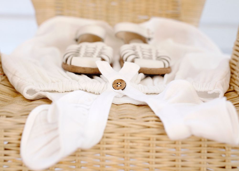 White cotton baby clothing with button detail on wicker basket.