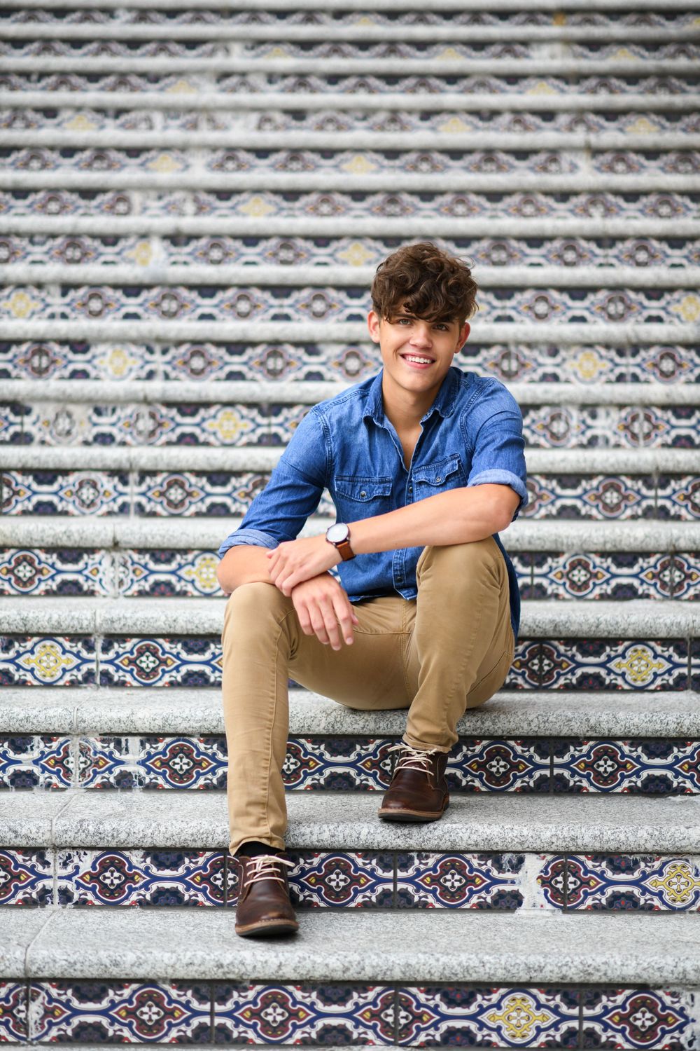 A casual portrait on decorative tiled steps showcasing relaxed style and denim fashion.