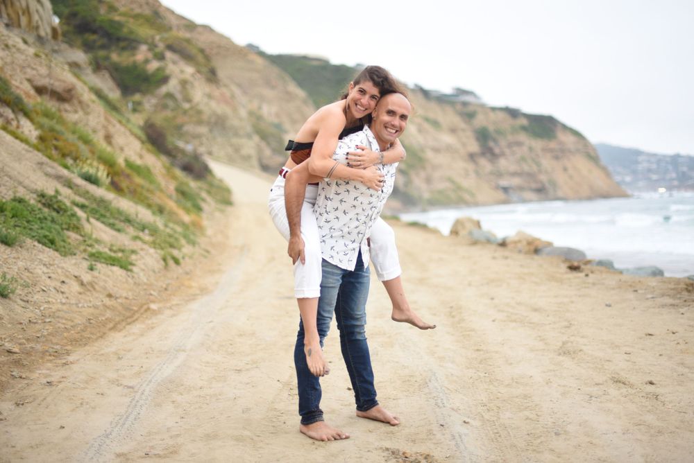 Couple laughing and walking together along scenic coastal cliff path.