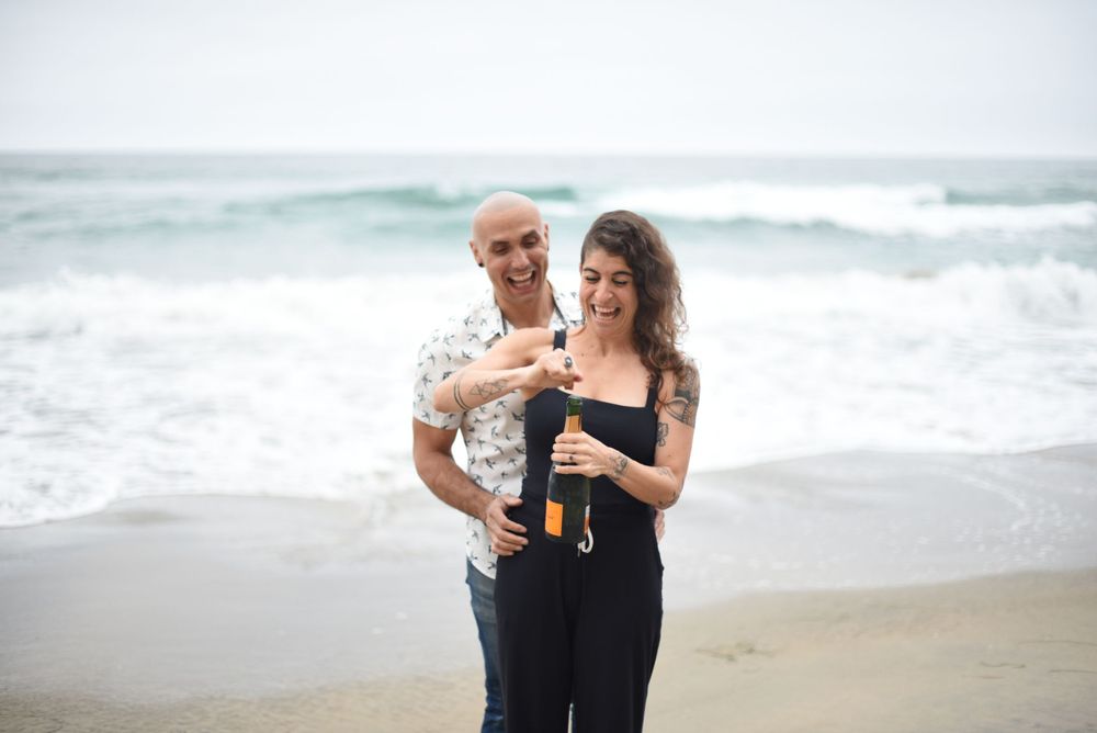 Couple toasting with drinks while enjoying romantic beach moment.