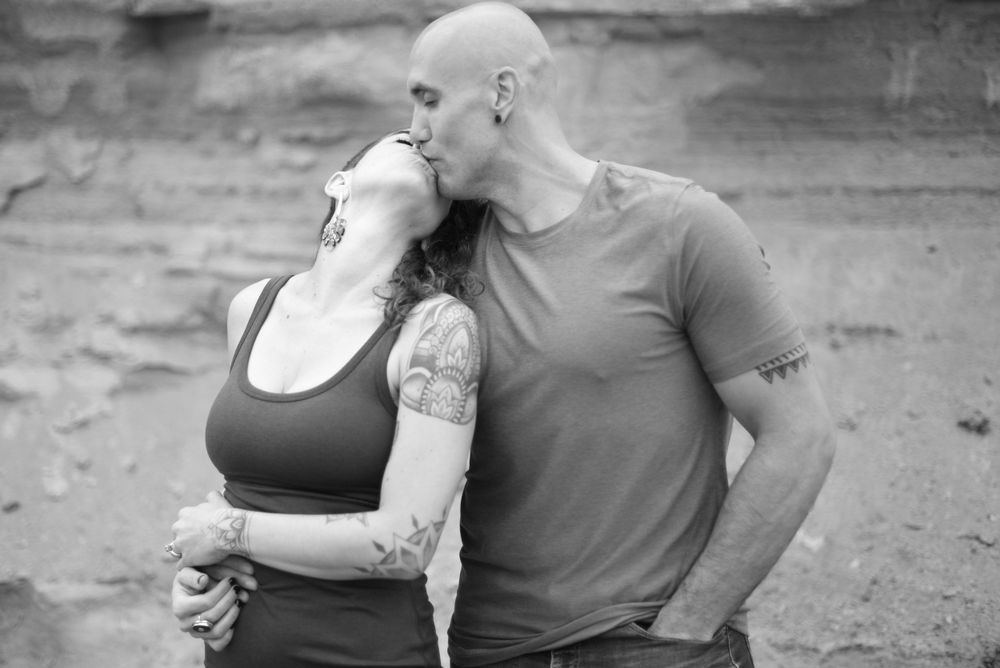 A couple embraces in black and white on a cloudy day.