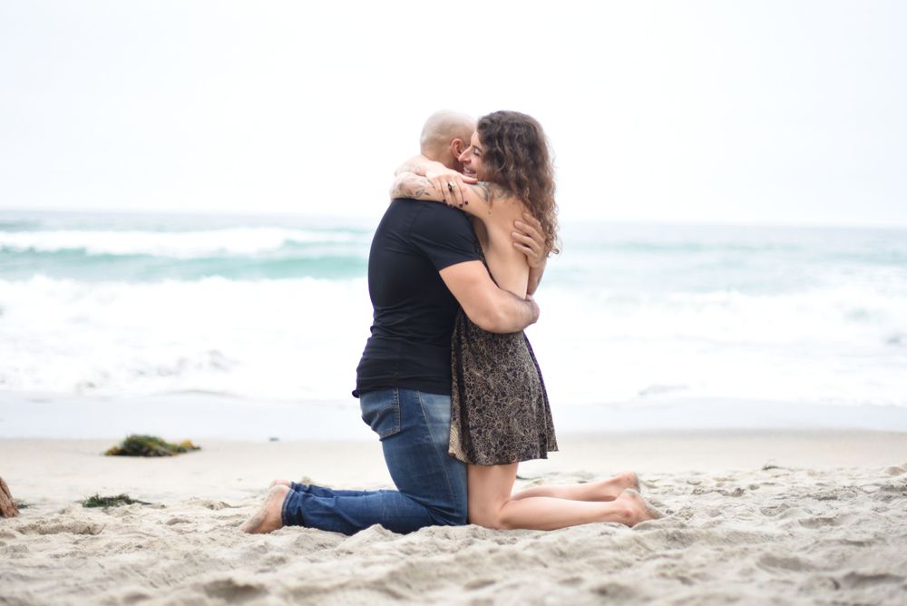 Romantic couple relaxing together on beach sand near crashing waves.
