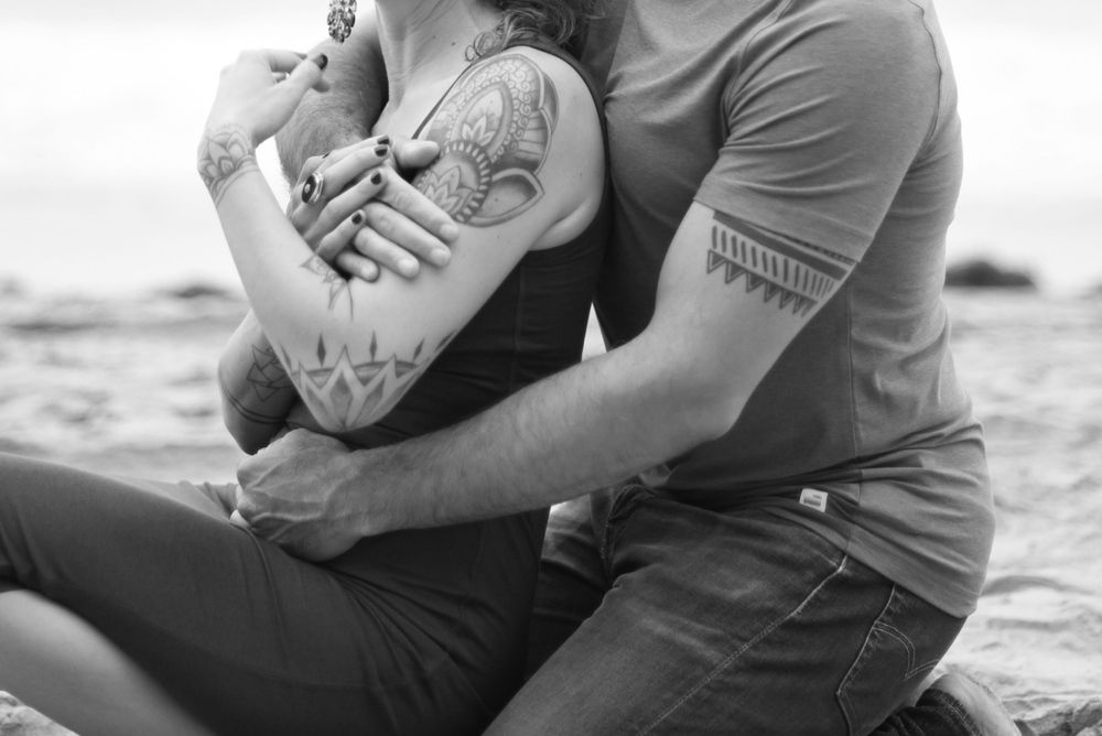 Close-up shot of couple embracing on sandy beach.