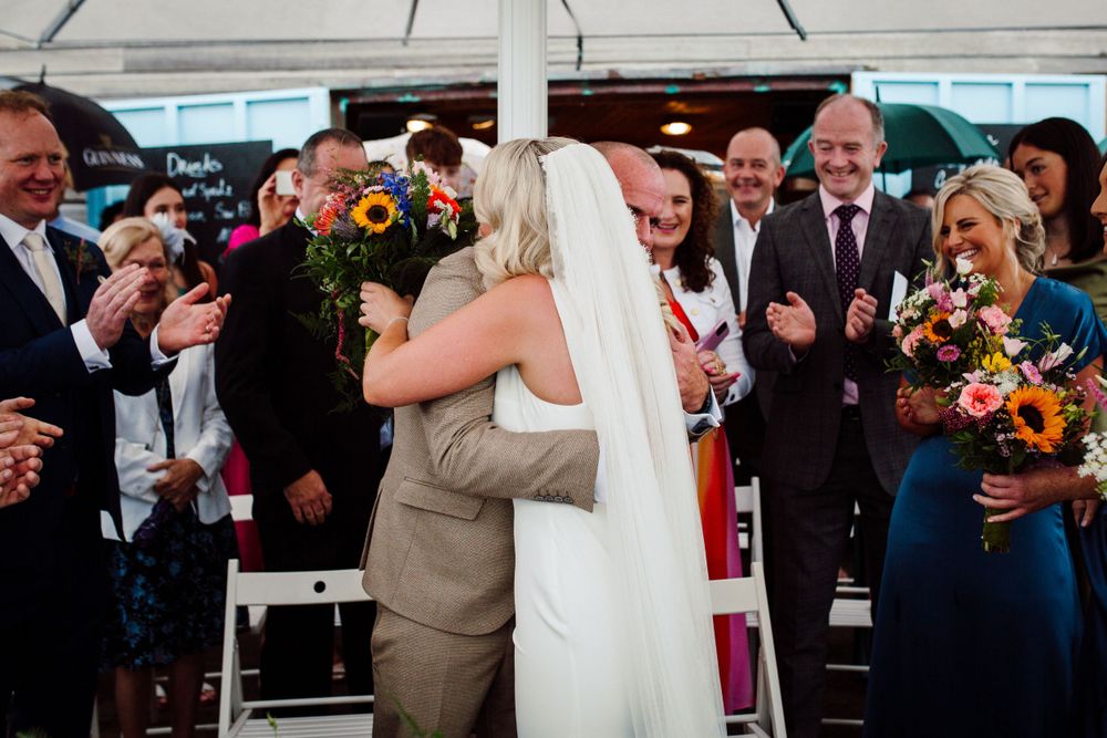 Emotional moment during outdoor wedding ceremony with guests watching.