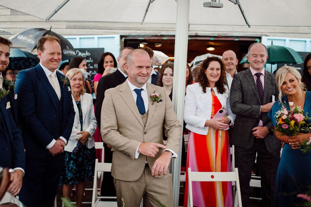 Wedding celebration under a white tent with guests watching and smiling.