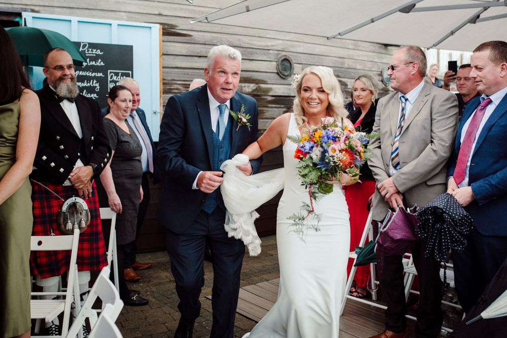 A wedding ceremony exit procession under a wooden deck covering.