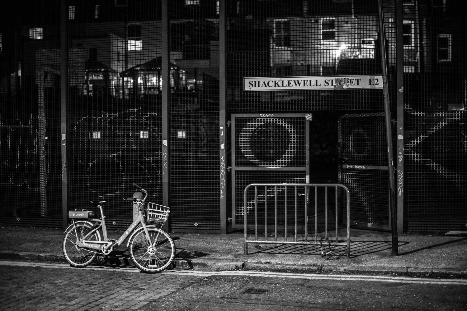 A lone bicycle parked against brick wall near bike rack on urban street.
