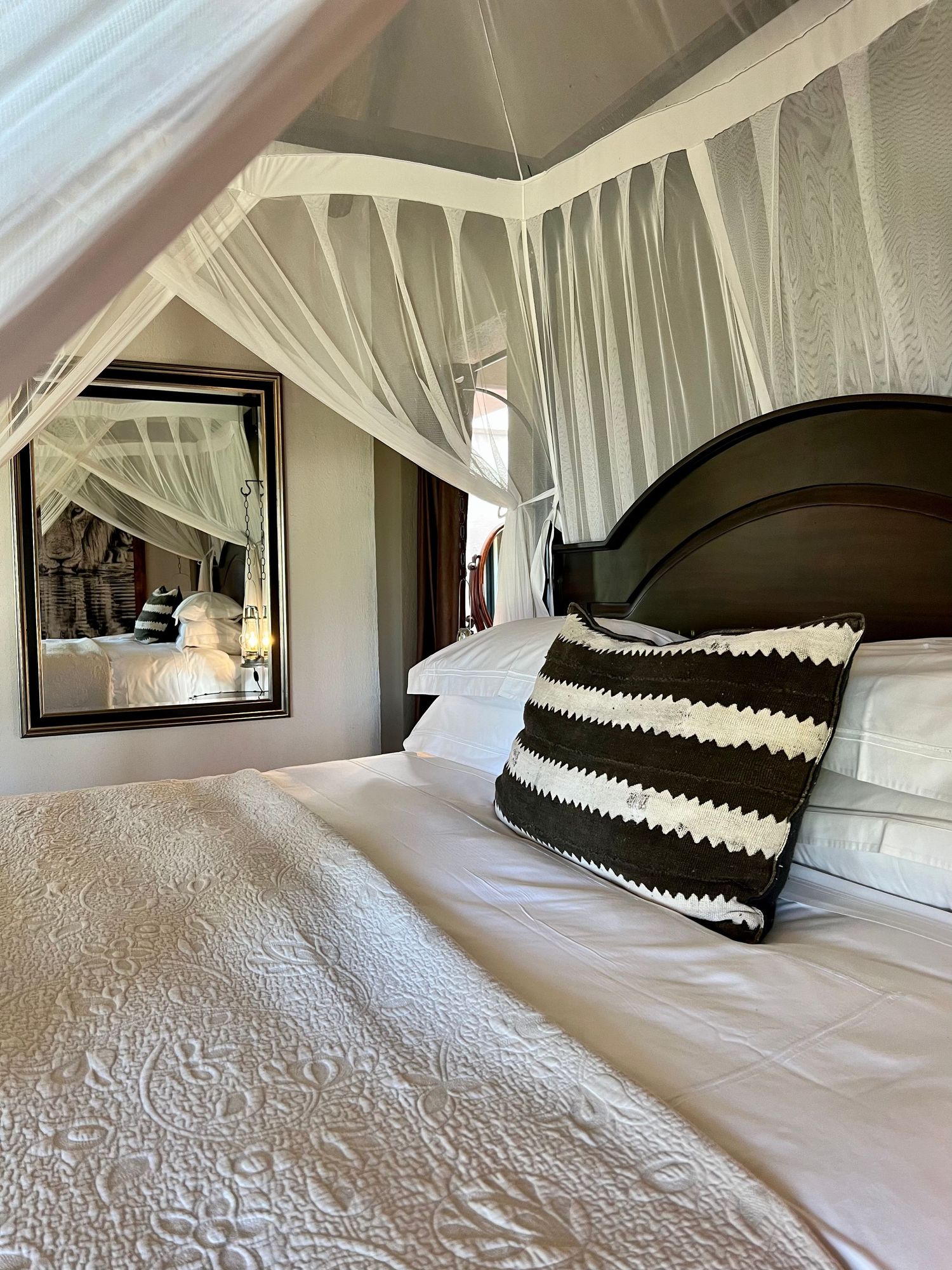 Luxurious bedroom with flowing white mosquito netting and black and white striped accent pillows.