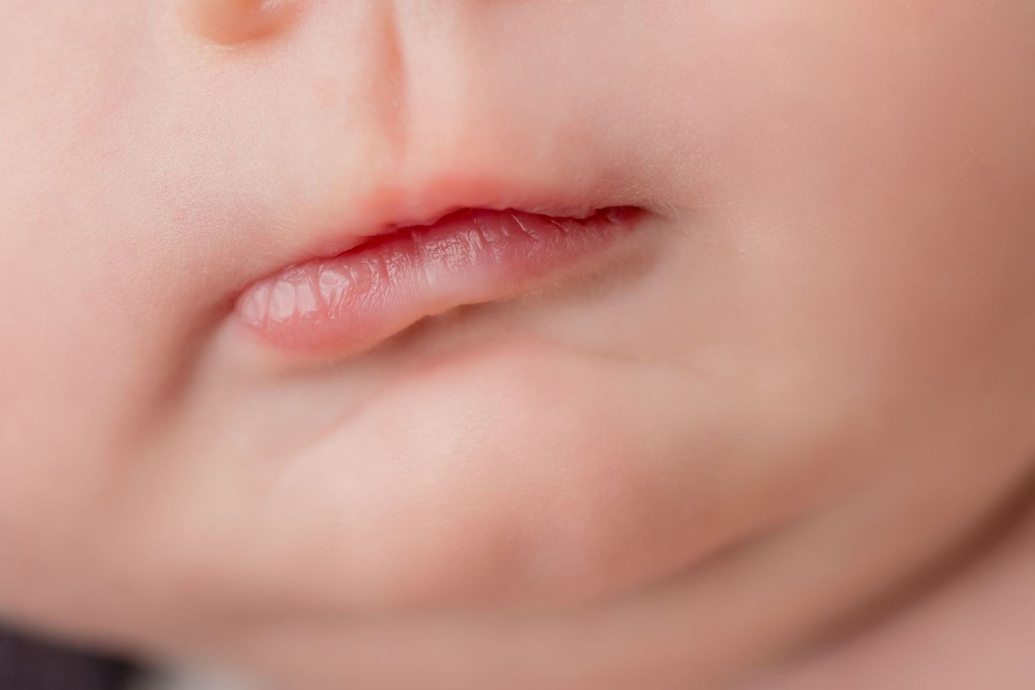 Close-up macro shot of sleeping newborn's pink lips and skin.